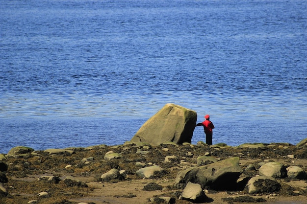 Foto achtergrondbeeld van een vrouw die op een rots bij de zee staat