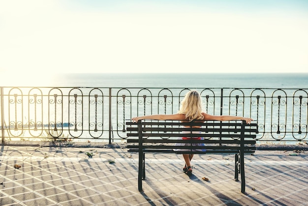 Achtergrondbeeld van een vrouw die op het strand zit bij de zee tegen een heldere lucht