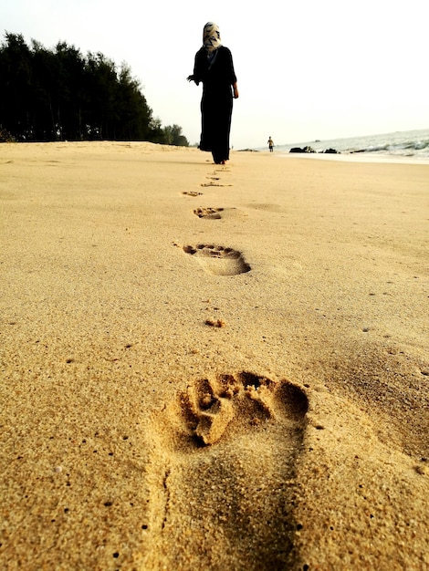 Foto achtergrondbeeld van een vrouw die op het zand op het strand loopt