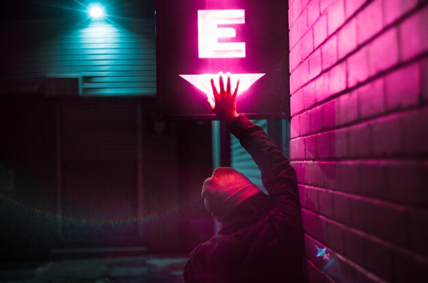 Foto achtergrondbeeld van een vrouw die's nachts een neonbord bij de muur aanraakt