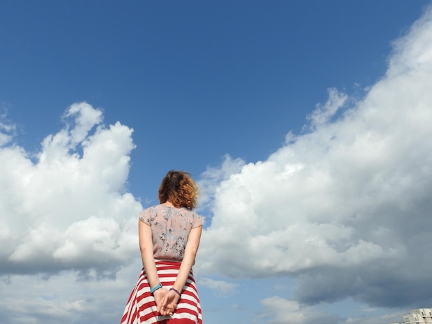 Achtergrondbeeld van een vrouw die tegen de blauwe hemel staat