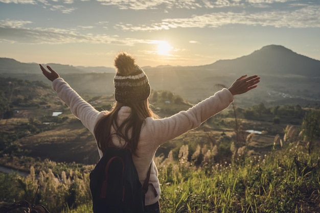 Achtergrondbeeld van een vrouw die tijdens de zonsondergang naar het landschap tegen de hemel kijkt