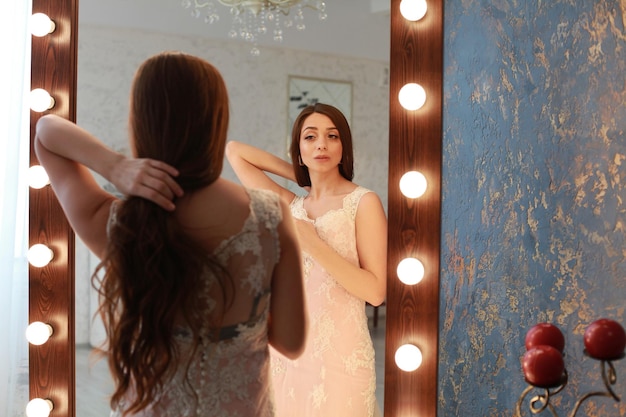 Foto achtergrondbeeld van een vrouw die voor een verlichte spiegel staat.