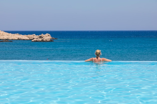 Foto achtergrondbeeld van een vrouw in een zwembad tegen de zee