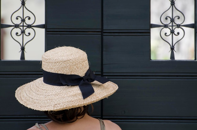 Foto achtergrondbeeld van een vrouw met een hoed die tegen een gesloten deur staat