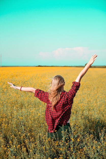 Achtergrondbeeld van een vrouw met haar armen omhoog op het veld tegen de lucht