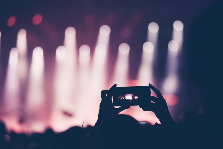 Foto achtergrondbeeld van een vrouw te midden van een menigte die op een muziekconcert fotografeert