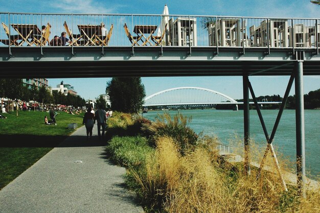 Foto achtergrondbeeld van mensen die onder een brug langs de rivier lopen