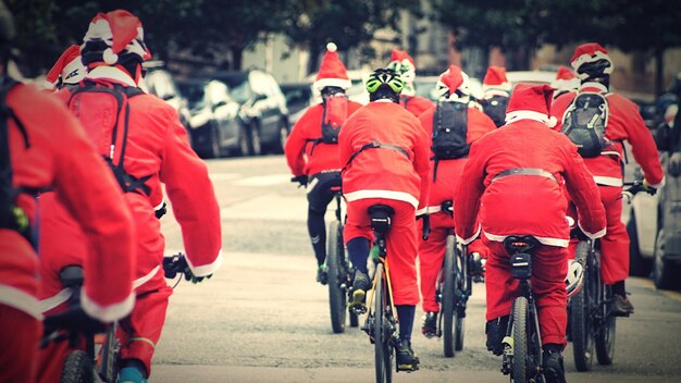 Foto achtergrondbeeld van mensen in een kerstmankostuum die fietsen in de stad