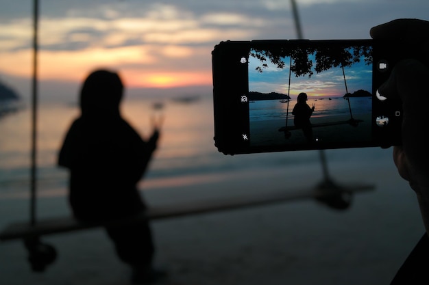 Foto achtergrondbeeld van silhouetten van mensen die tijdens de zonsondergang zee tegen de hemel fotograferen