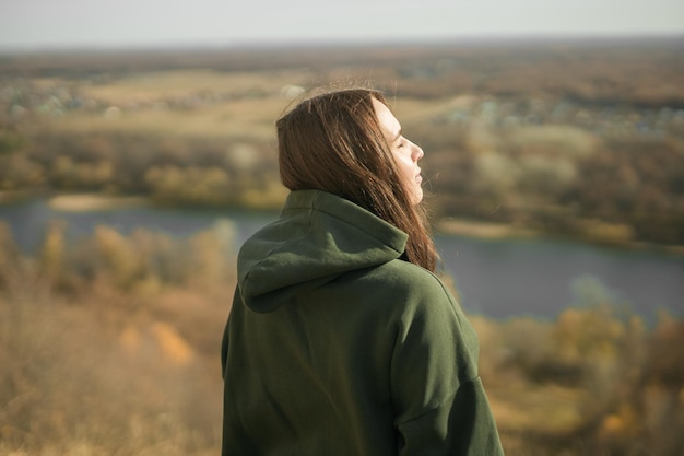 Achtergrondbeeld van trendy jonge vrouw in donkergroene hoodie in de herfst schattig model loopt in het park in gouden