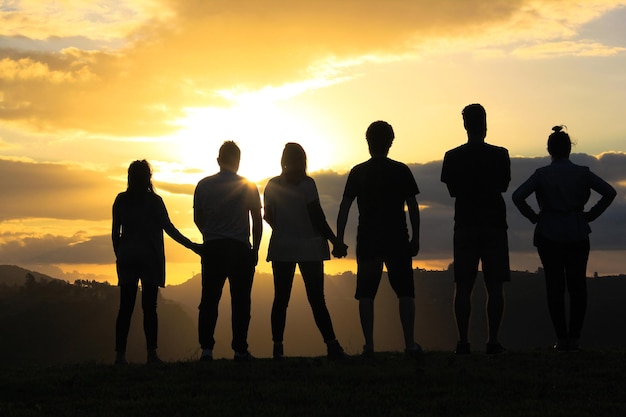 Achtergrondbeeld van vrienden die tijdens de zonsondergang op het veld tegen de lucht staan