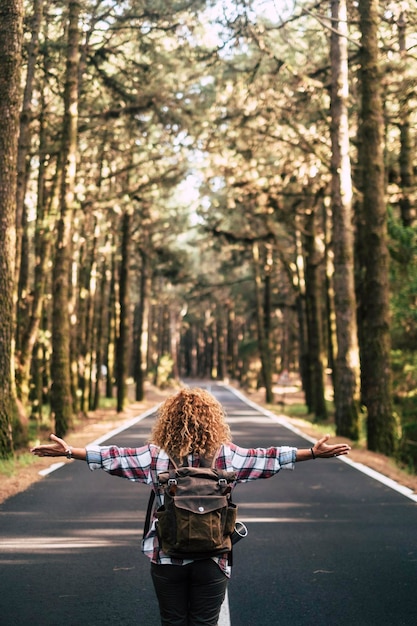 Foto achtergrondbeeld van vrouw met uitgestrekte armen die op de weg in het bos staat