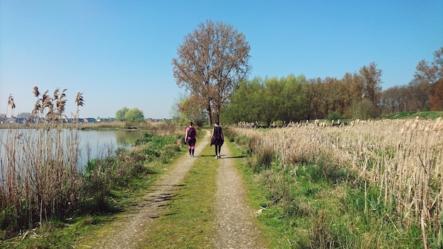 Foto achtergrondbeeld van vrouwen die op het voetpad langs het meer lopen tegen de lucht