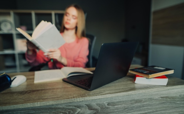 Achtergrondfoto in onscherpe Een vrouwelijke student studeert thuis op afstand houdt een boek vast