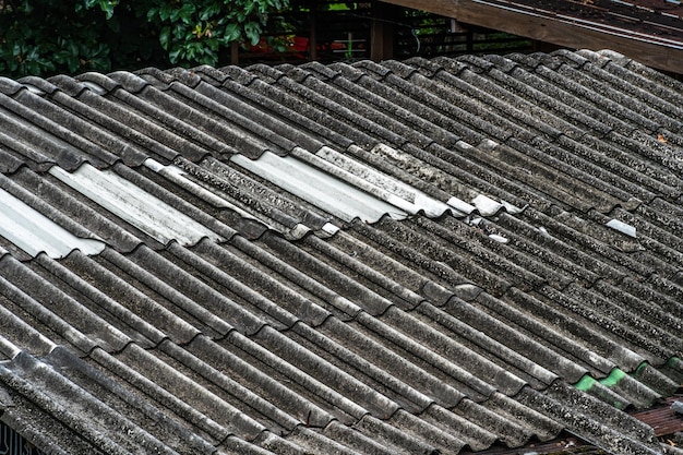 Foto achtergrondtegeltextuur van daklei op het dak van zwart en grijs begroeid met korstmos en mos van het oude huis ruw oppervlak pannendak op een gebouw