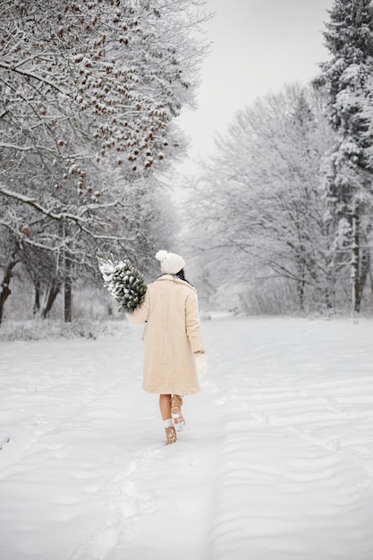 Achterkant portret van een vrouw die op winterdag in het bos loopt