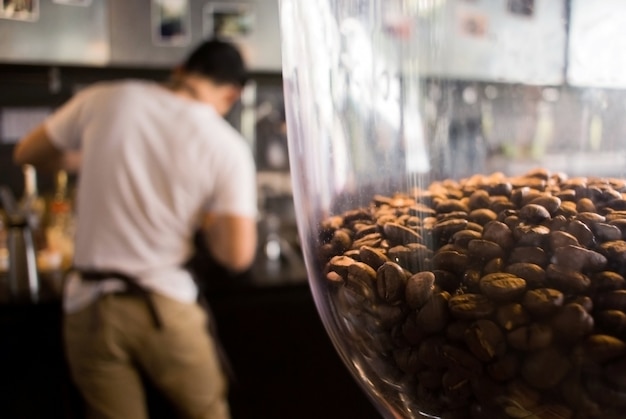 Achterkant van barista die met koffiemachine werken.