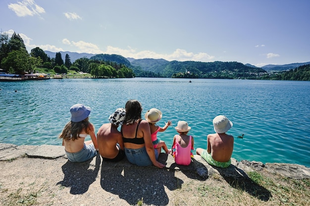 Achterkant van de vrouw met vijf kinderen zit op de pier van het prachtige Bled-meer, Slovenië Moeder van veel kinderen