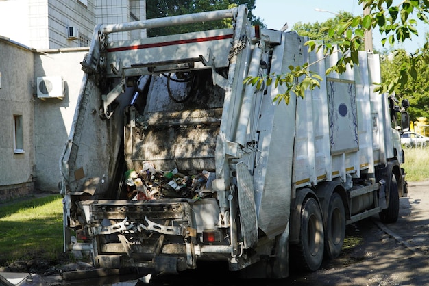 Achterkant van een stadsvuilniswagen met afval Vuilniswagen op het werk achteraanzicht