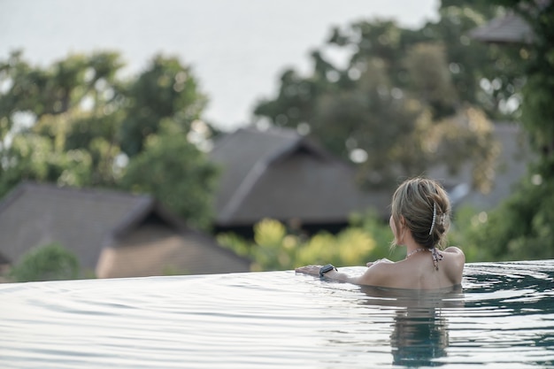 Achterkant van een vrouw in zwembad, zomervakantie.