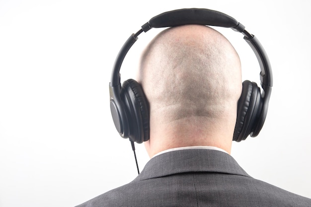 Achterkant van het hoofd van een man met koptelefoon in ontspanning luisteren naar muziek op een lichte achtergrond