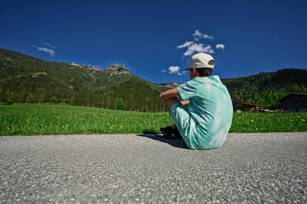 Achterkant van jongen zit op pad in alpenweide bij untertauern austria