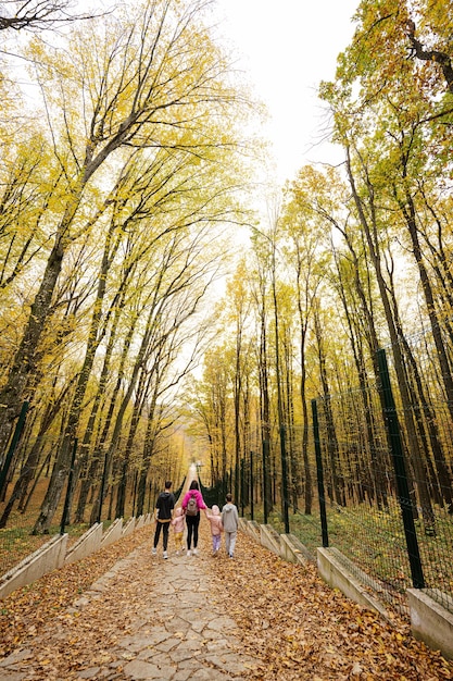 Achterkant van moeder met vier kinderen op pad in herfstbos