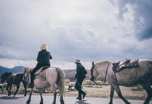 Foto achterkant vrouw paardrijdt door man op weg tegen bewolkte lucht