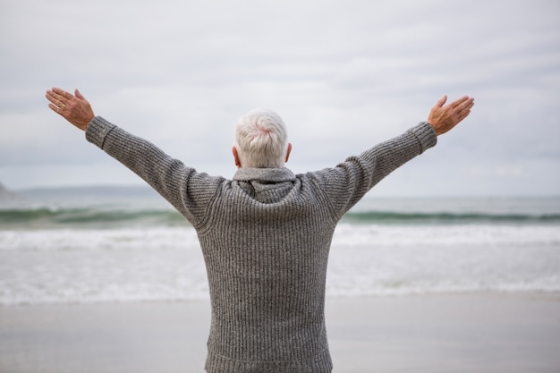 Achtermening die van de hogere mens zich met wapens uitgestrekt op strand bevinden