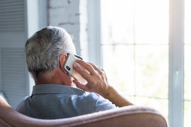 Foto achtermening van de hogere mens die op cellphone spreken