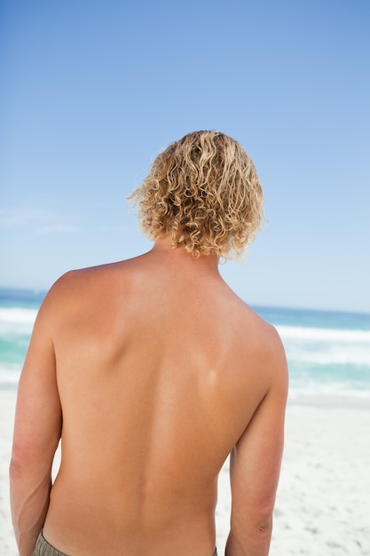 Achtermening van een jonge blondemens die de oceaan bekijken
