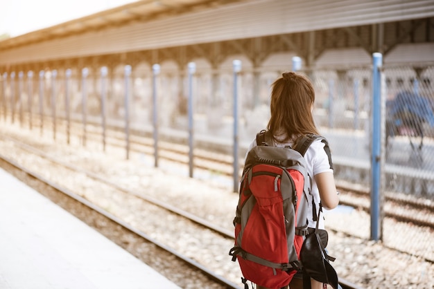 Achtermening van jonge Aziatische vrouwentoerist die op trein bij station wacht