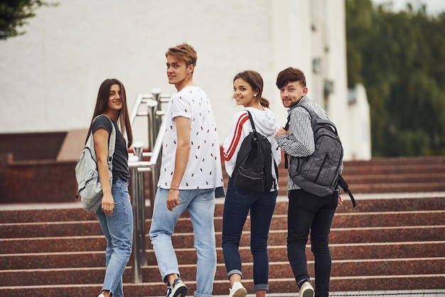 Achterom kijken. Achteraanzicht. Groep jonge studenten in vrijetijdskleding in de buurt van de universiteit overdag.