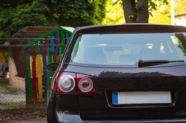 Achterruit van zwarte auto geparkeerd op straat in zonnige zomerdag, achteraanzicht. Mock-up voor sticker of stickers