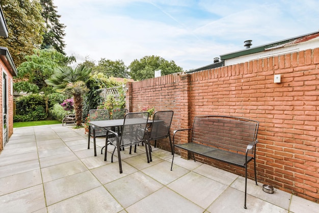 Achtertuin van het huis met zwarte rieten stoelen en tafel