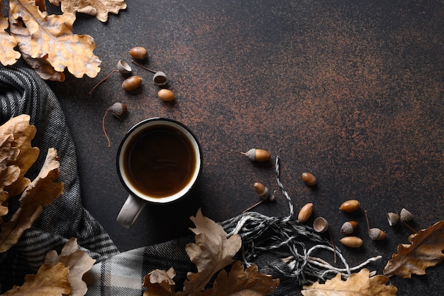 Acorn coffee in cozy lifestyle on brown table with fall oak leaves and cozy scarf. Concept coffee substitute without caffeine. View from above. Space for text.