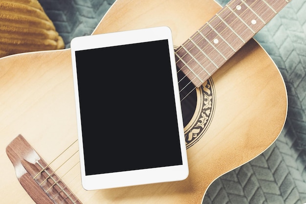 Photo acoustic guitar and digital tablet on couch