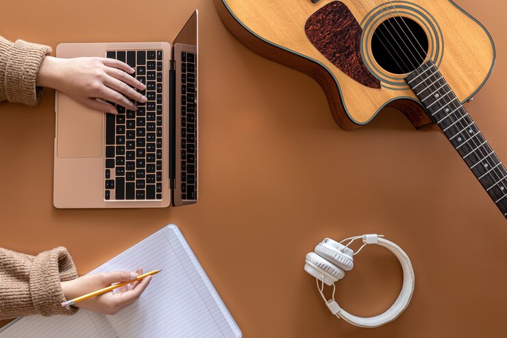 アコースティックギター、女性の手はラップトップの後ろで動作します。これは音楽を作成するという概念です。