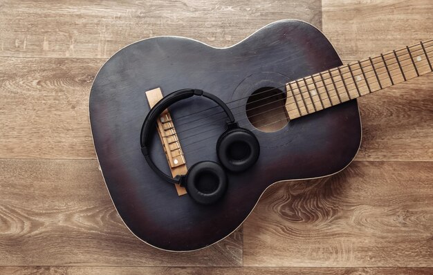 Acoustic guitar and headphones on wooden floor online guitar
lessons musical concept top view flat lay