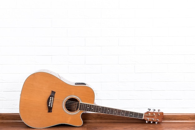 Acoustic guitar leans on a white brick wall