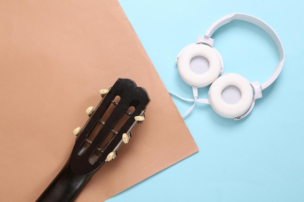 Acoustic guitar neck and headphones on brown blue background\
online guitar lessons musical concept top view flat lay