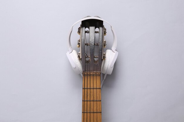 Acoustic guitar neck and headphones on gray background online\
guitar lessons musical concept top view flat lay