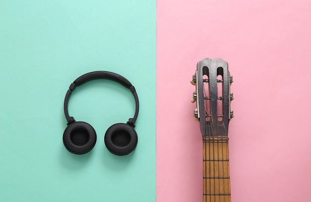 Acoustic guitar neck and headphones on pink blue background\
online guitar lessons musical concept top view flat lay