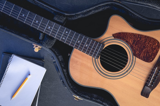 Acoustic guitar and notepad with pencil top view