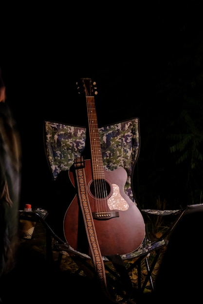 Acoustic guitar resting in camping chair on background dark\
with copy space. classic guitar