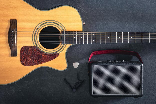 Acoustic guitar and speaker on a black background top view