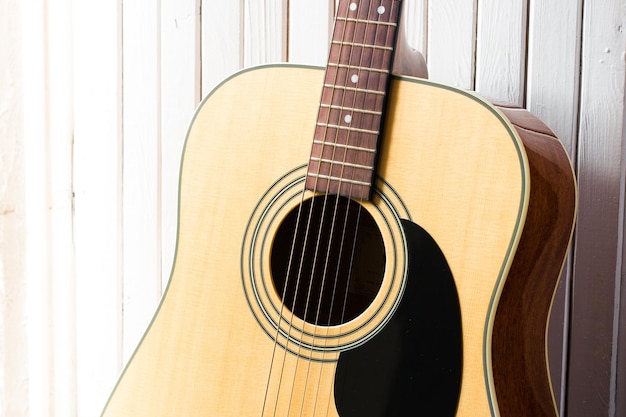 Acoustic guitar on a white wooden background closeup