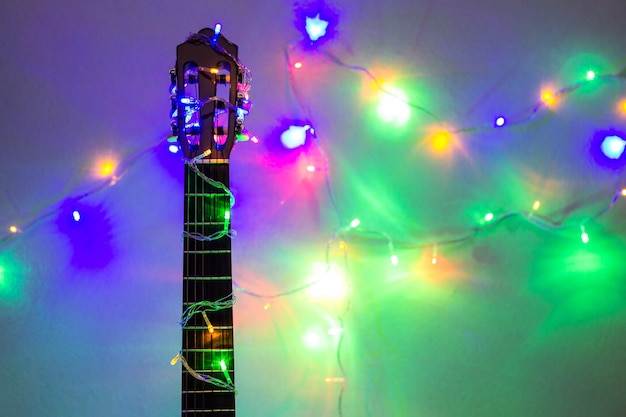 Acoustic guitar wrapped by colorful garland. christmas and new year music gift as background