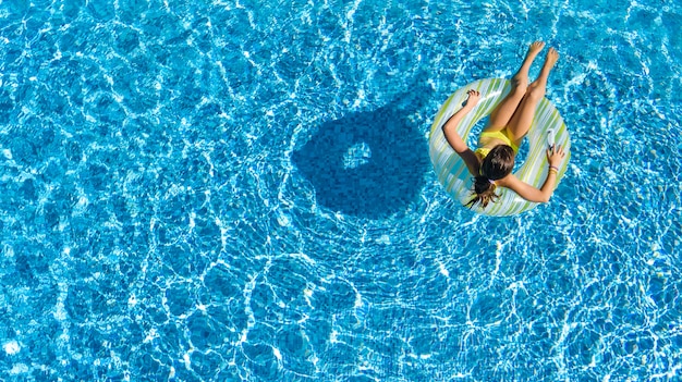 Acrive meisje in zwembad luchtfoto bovenaanzicht van bovenaf, kind zwemt op opblaasbare ring donut, kind heeft plezier in blauw water op familievakantie resort